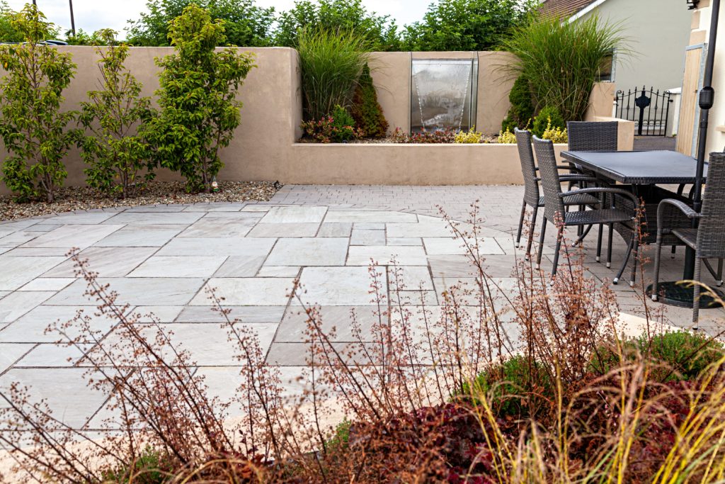 grey-sandstone-patio-with-joint-it-simple-and-shrubbery 